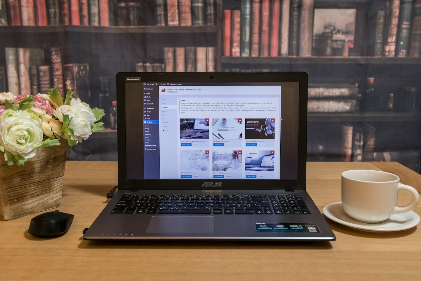 Laptop con interfaccia di backend di un sito web, accanto a ranuncoli e una tazza di caffè.