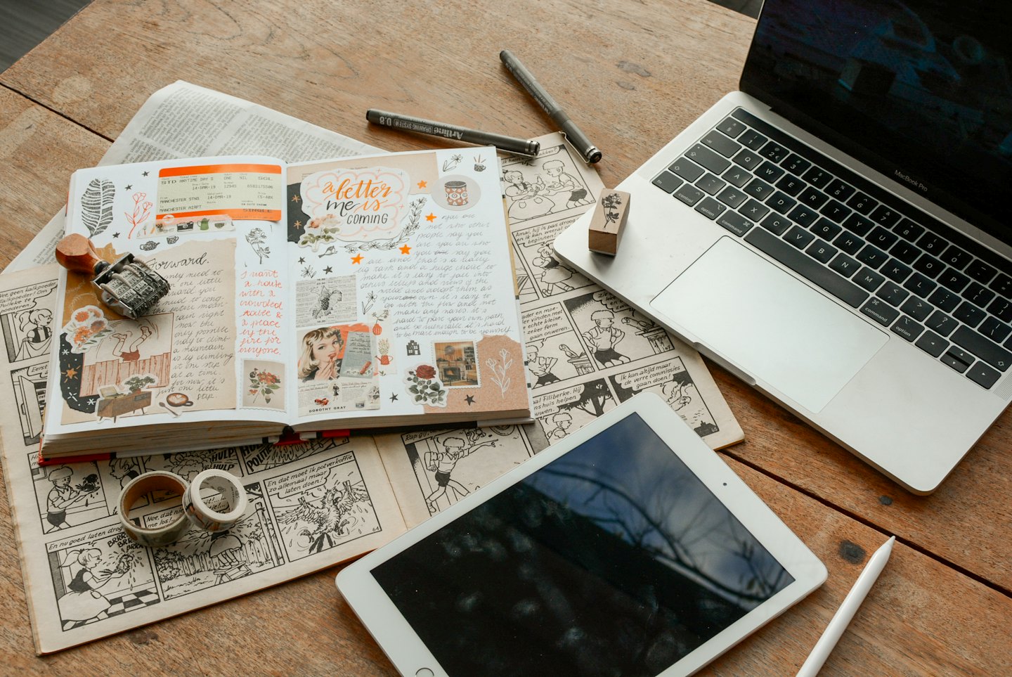 Un laptop e un tablet appoggiati su un diario pieno di adesivi.